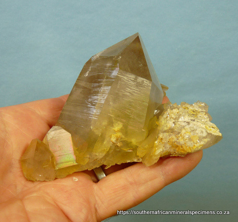 Light smoky quartz crystal sitting on a quartz plate